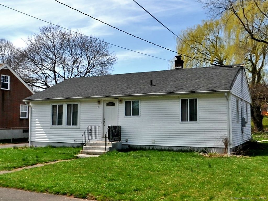 view of front facade featuring a chimney, a front yard, and roof with shingles