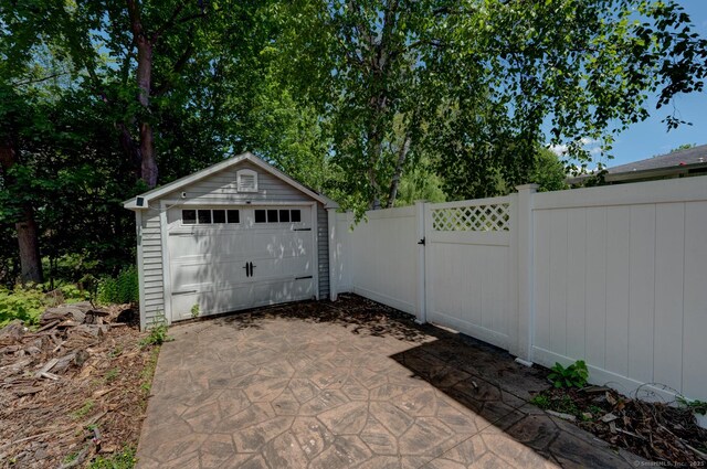 detached garage with driveway, fence, and a gate