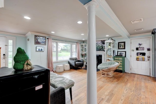 living room featuring crown molding, a fireplace, light wood-type flooring, healthy amount of natural light, and recessed lighting