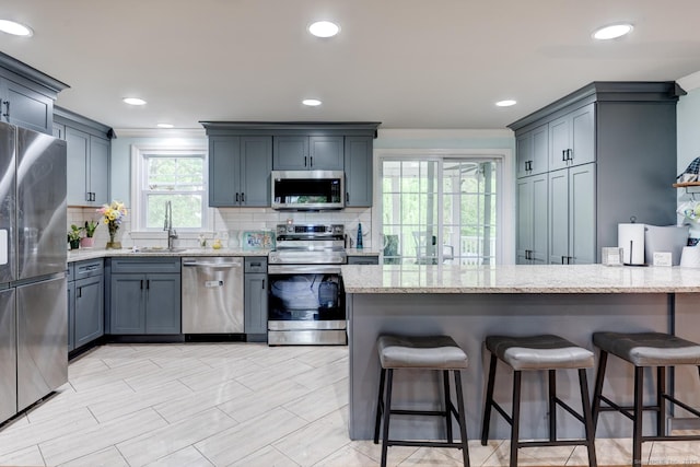 kitchen featuring stainless steel appliances, a sink, a peninsula, backsplash, and recessed lighting