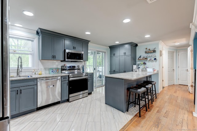 kitchen with stainless steel appliances, a sink, a peninsula, crown molding, and a breakfast bar area