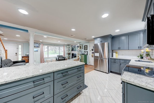 kitchen featuring freestanding refrigerator, open floor plan, ornate columns, a sink, and recessed lighting