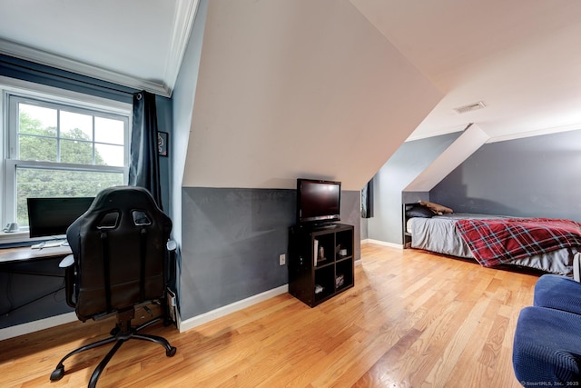 bedroom with a desk, wood finished floors, baseboards, and ornamental molding