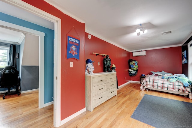 bedroom with ornamental molding, light wood-style flooring, baseboards, and a wall mounted air conditioner