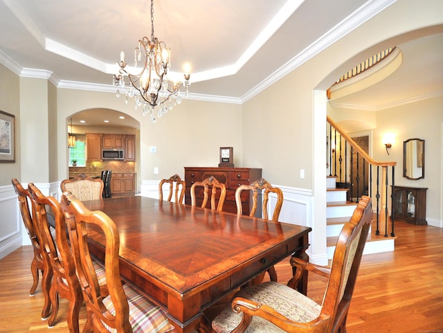 21 Pheasant Hill Rd, Canton, CT 06019 - dining room with a tray ceiling, light wood-type flooring, arched walkways, a chandelier, and a wainscoted wall