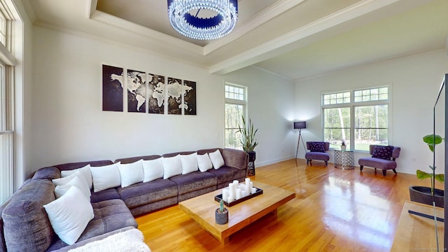 living room with wood finished floors, a chandelier, crown molding, a tray ceiling, and baseboards