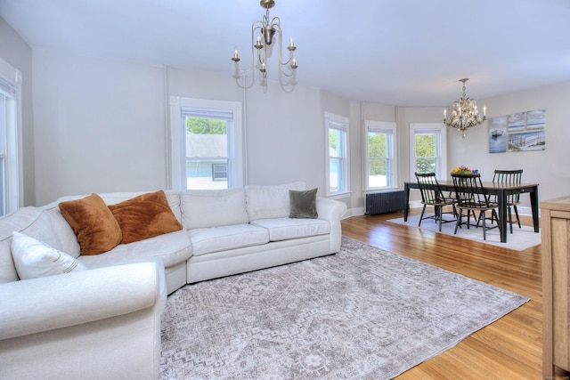 living room with a chandelier, wood finished floors, plenty of natural light, and radiator heating unit
