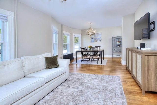 living room featuring a chandelier, light wood finished floors, and baseboards