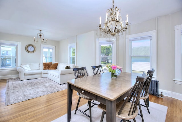 dining space featuring a chandelier, radiator heating unit, healthy amount of natural light, and baseboards