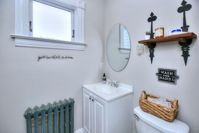 half bath with radiator heating unit, toilet, and vanity