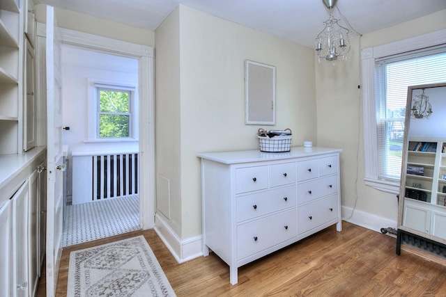 doorway to outside with a chandelier, light wood finished floors, and baseboards
