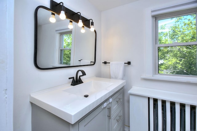bathroom with healthy amount of natural light, vanity, and radiator