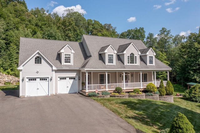 view of front of property featuring driveway, covered porch, a front yard, a garage, and a shingled roof