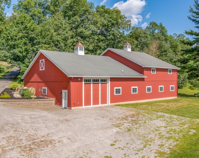 view of outbuilding with dirt driveway and view of wooded area