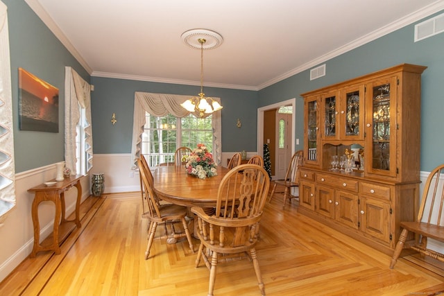 dining room featuring a chandelier, a wainscoted wall, and crown molding