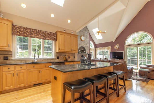 kitchen with a skylight, a sink, open floor plan, plenty of natural light, and high vaulted ceiling