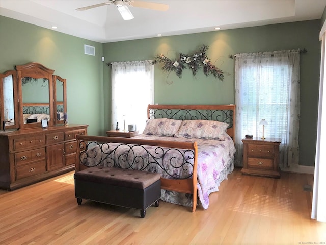 bedroom featuring a raised ceiling, light wood-style floors, a ceiling fan, and recessed lighting