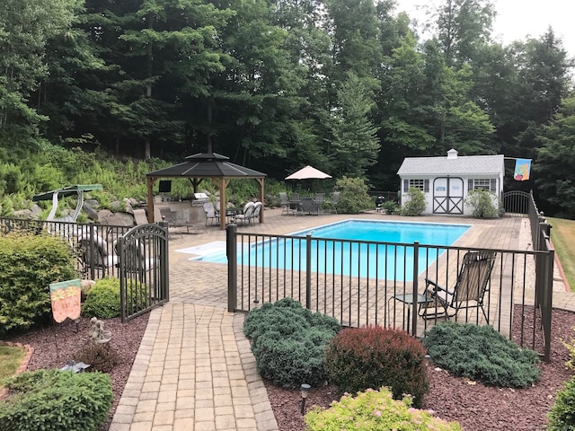 view of pool featuring a gazebo, a patio area, fence, and an outbuilding