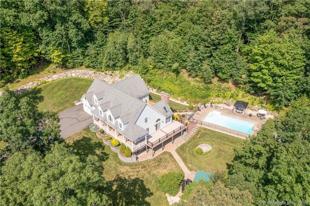 aerial view of property and surrounding area featuring a pool area and a forest