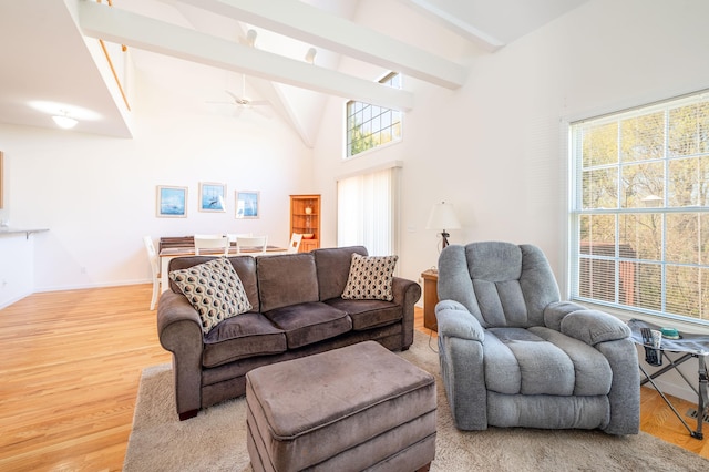 living room featuring beam ceiling, light wood-style flooring, a ceiling fan, baseboards, and high vaulted ceiling