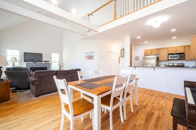 dining space featuring high vaulted ceiling, light wood-style floors, recessed lighting, and a fireplace