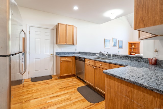 kitchen featuring stainless steel appliances, light wood-style flooring, a sink, dark stone countertops, and recessed lighting