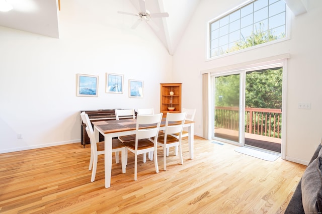 dining space featuring wood finished floors, a towering ceiling, a ceiling fan, and baseboards