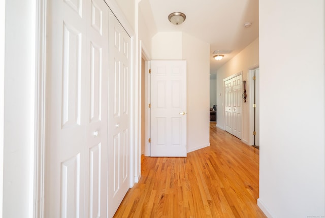 corridor featuring light wood finished floors and baseboards