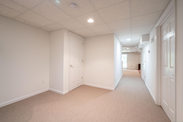 hall with light carpet, baseboards, a drop ceiling, and recessed lighting