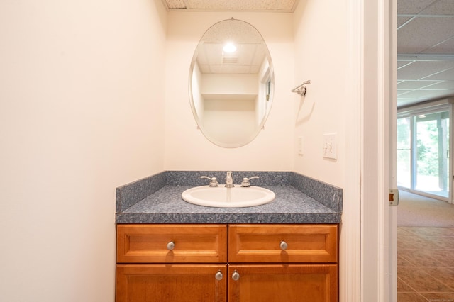bathroom with vanity, a drop ceiling, and tile patterned flooring