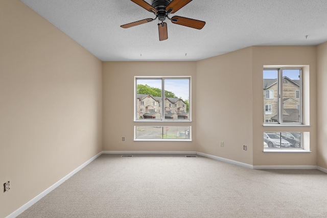 carpeted spare room featuring baseboards, a ceiling fan, and a textured ceiling