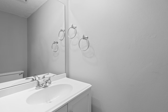 bathroom with a textured ceiling, vanity, and toilet