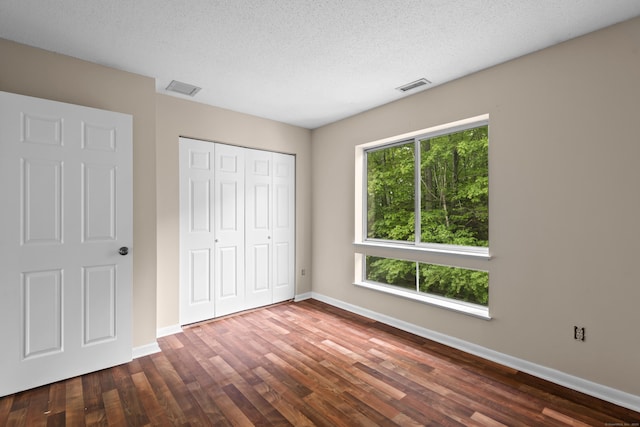 unfurnished bedroom with dark wood-style flooring, baseboards, and a textured ceiling