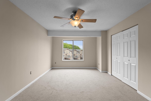 unfurnished bedroom with carpet, baseboards, a textured ceiling, a closet, and ceiling fan