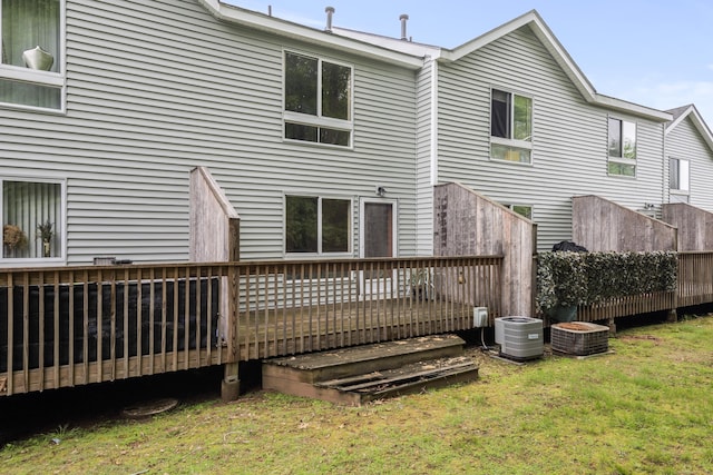 back of house featuring cooling unit, a lawn, and a wooden deck
