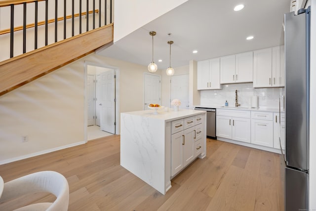 kitchen with stainless steel appliances, light wood finished floors, a sink, recessed lighting, and white cabinets