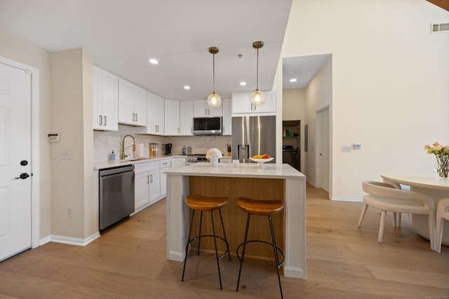 kitchen featuring appliances with stainless steel finishes, light wood-style flooring, light countertops, a sink, and white cabinetry