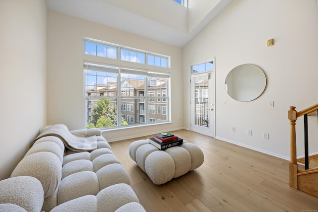 living area featuring wood finished floors, a high ceiling, baseboards, and stairway