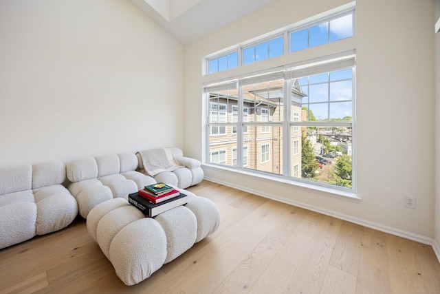 living room with baseboards, high vaulted ceiling, and wood finished floors