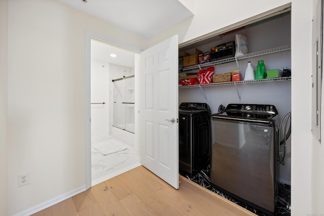 laundry area featuring washing machine and dryer, marble look tile flooring, and baseboards