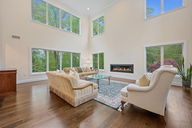 43 Hunting Ridge Rd, Greenwich, CT 06831 - living room featuring a high ceiling, a glass covered fireplace, baseboards, wood finished floors, and crown molding