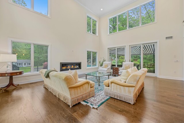 43 Hunting Ridge Rd, Greenwich, CT 06831 - living room with a towering ceiling, wood finished floors, plenty of natural light, a glass covered fireplace, and baseboards