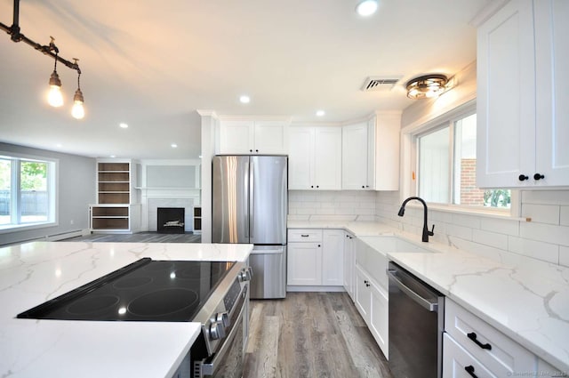 kitchen featuring appliances with stainless steel finishes, a sink, backsplash, light wood-type flooring, and recessed lighting