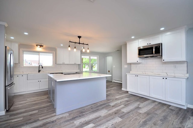 kitchen with stainless steel appliances, a sink, decorative backsplash, light wood finished floors, and recessed lighting