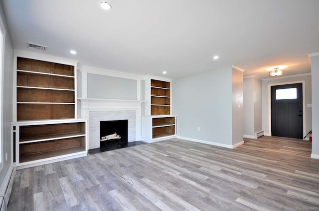 unfurnished living room with baseboards, crown molding, wood finished floors, recessed lighting, and built in features