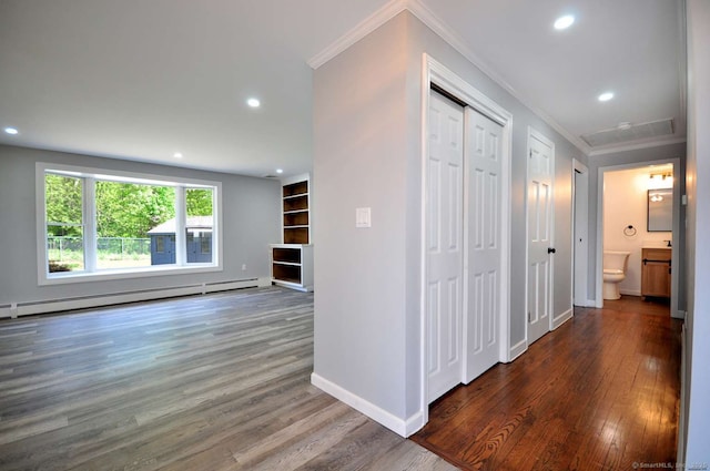 hall featuring a baseboard heating unit, crown molding, wood finished floors, recessed lighting, and baseboards