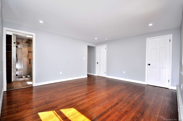 empty room featuring dark wood-style floors, baseboards, recessed lighting, and a baseboard heating unit