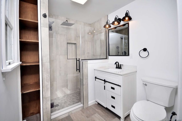 bathroom featuring toilet, a shower stall, vanity, and wood finished floors