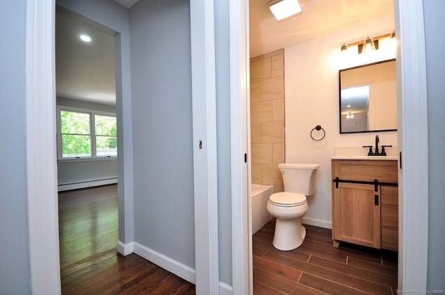 full bath with baseboard heating, wood finished floors, toilet, vanity, and baseboards
