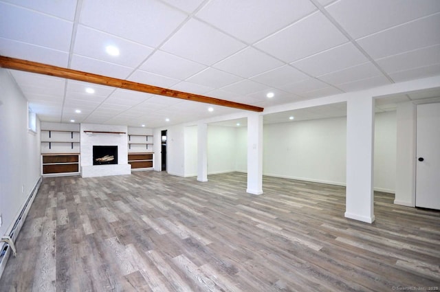 finished below grade area with wood finished floors, baseboards, recessed lighting, a paneled ceiling, and a fireplace